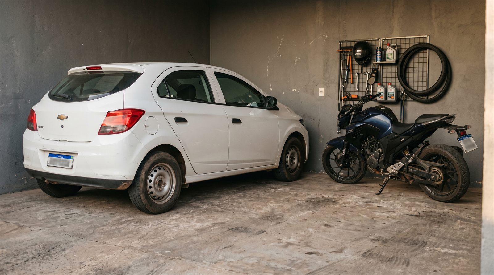 Chevrolet Onix branco e moto Yamaha em garagem limpa